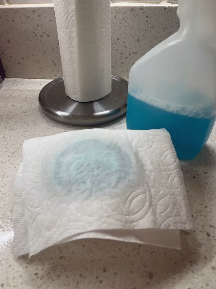 Dung dịch lau kính được xịt lên giấy ăn để loại bỏ nhãn dán giá.